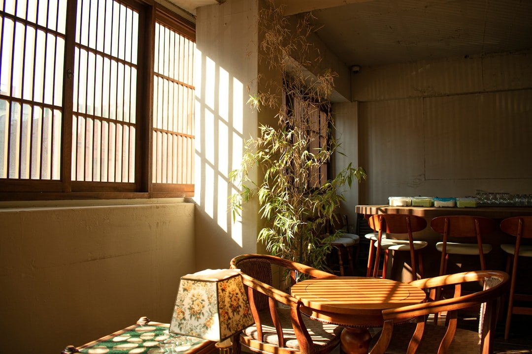 Cozy neighborhood cafe interior with exposed brick walls and sunlight streaming through windows onto wooden tables set for brunch